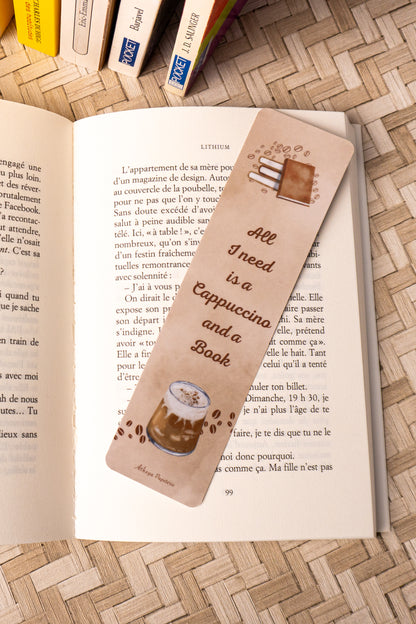 Marque-pages sur lequel on peut lire "All I need is a Cappuccino and a Book" avec au dessus de la citation une jolie pile de livre et en dessous, le dessins d'un beau cappuccino.