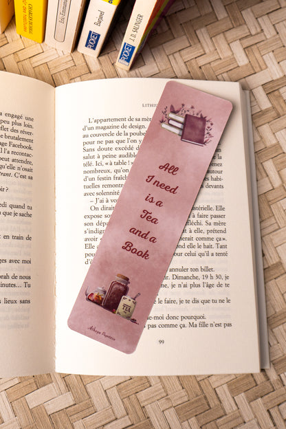 Marque-pages sur lequel on peut lire "All I need is a Tea and a Book" avec au dessus de la citation une jolie pile de livre et en dessous, le dessins d'un beau thé.
