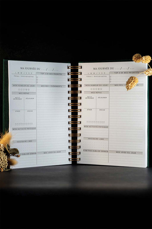 Photo de l'intérieur de l'agenda Lea qui est sur un fond noir. Les seuls éléments décoratifs que l'on aperçoit sont quelques fleurs séchées.