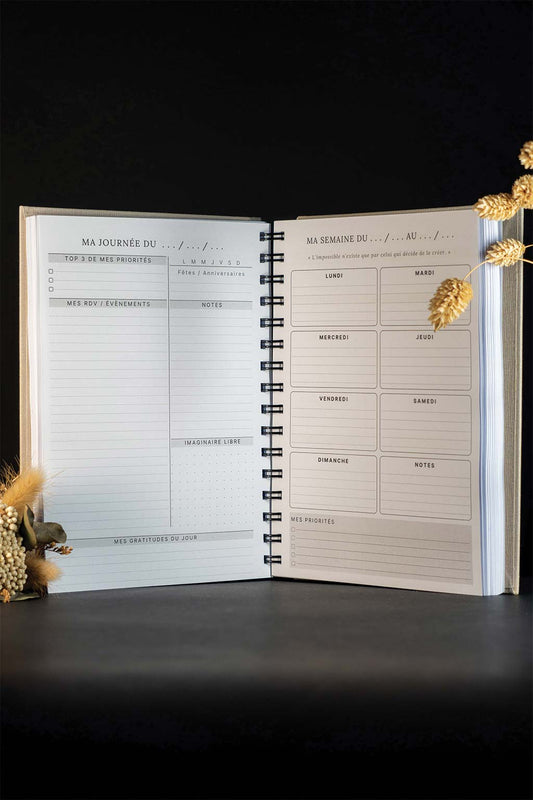 Photo de l'intérieur de l'agenda Rose qui est sur un fond noir. Les seuls éléments de décoration que l'on aperçoit sont des fleurs séchées.