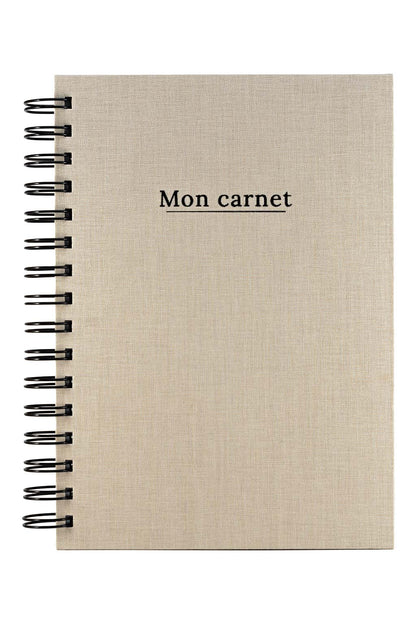 Photo brute du carnet "Mon Carnet" recouvert d'une toile beige et  avec l'inscription "Mon carnet" ainsi que la spirale de couleur noire. Il n'y a aucun autre élément sur la photo, uniquement le carnet sur fond blanc.